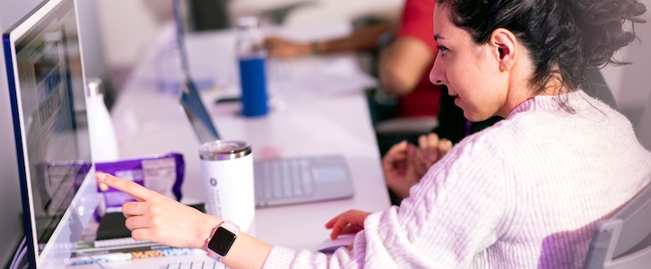 Photo of a student pointing at a computer screen.