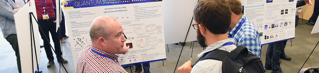 Faculty members talking and reviewing a poster presentation.